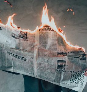 Hombre leyendo un periódico en llamas