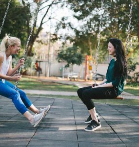 Amigas platicando en un columpio.